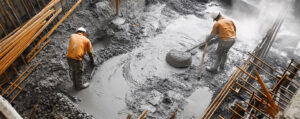 Workers mixing Ordinary Portland Cement concrete at a construction site, showcasing its applications and strength – Amrit Cement.